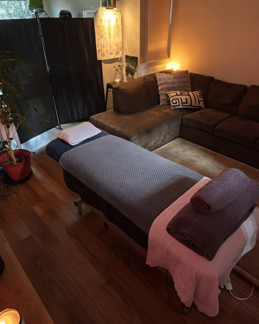 The Aligned Bodywork studio — massage table with fresh towels, warm candlelight and plants